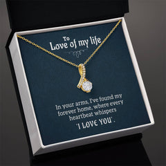 Gold necklace with a delicate ribbon-shaped pendant featuring a sparkling clear stone, displayed in a gift box with a romantic message for a loved one.