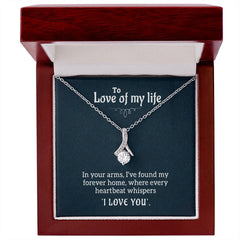Elegant silver necklace with a ribbon-shaped pendant featuring a sparkling gemstone, displayed in a polished wooden gift box with a heartfelt message inside.
