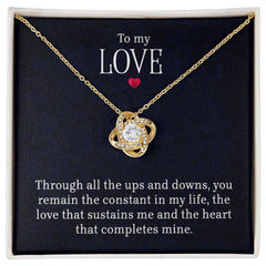 Gold necklace with a sparkling cubic zirconia pendant in a love knot design, presented on a card with a romantic message expressing unwavering love and devotion.