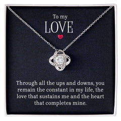 Silver love knot necklace with cubic zirconia stones displayed in a branded gift box featuring a heartfelt message expressing enduring love and commitment.
