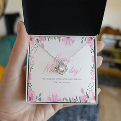Silver love knot necklace displayed in an open gift box with a floral-themed sentimental Mother's Day message card expressing love and appreciation.