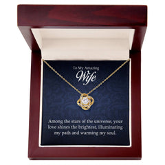 Elegant gold love knot necklace with a sparkling center stone, displayed in a dark wood gift box with a heartfelt message for an amazing wife.