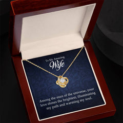 Gold love knot necklace with a sparkling center stone displayed in an elegant wooden box with a heartfelt message for a wife, perfect as a sentimental gift.