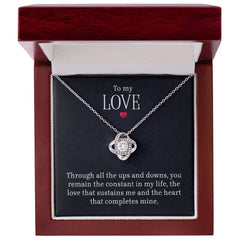 Elegant silver love knot necklace with cubic zirconia stones displayed in a polished wooden gift box featuring a heartfelt romantic message.