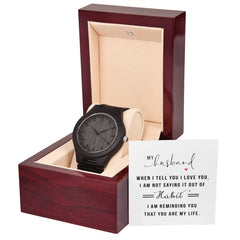 Elegant dark wooden watch with black dial and strap, displayed in a polished wooden gift box alongside a heartfelt note for a husband expressing love and appreciation.