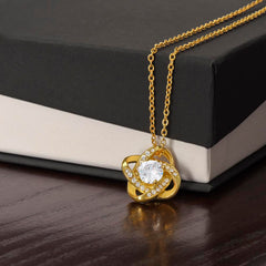Love Knot Necklace in gold-tone with a central crystal surrounded by pavé stones on a gold chain.
