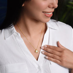 Love Knot Necklace, gold-tone pendant on a delicate chain worn by a woman in a white blouse as she smiles