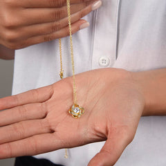 Love Knot necklace, gold-tone chain with crystal centerpiece, held in palm