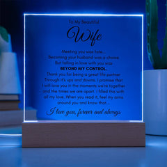A glowing acrylic square plaque with a heartfelt love message illuminated by blue LED light, displayed on a wooden base as a sentimental gift for a wife.