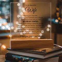 Clear acrylic plaque with heartfelt romantic message for a wife, mounted on a wooden base that softly lights up, displayed on a stack of books in a cozy setting.