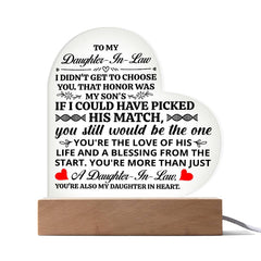 Heart-shaped acrylic plaque with a heartfelt message for a daughter-in-law, illuminated on a wooden base, symbolizing love and appreciation.