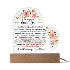 Heart-shaped LED acrylic plaque with floral accents and a sentimental message from a parent to their daughter, displayed on a wooden base.