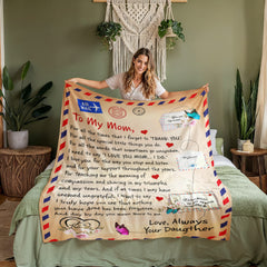 Woman holding a coral fleece blanket with a heartfelt letter design expressing love and gratitude from a daughter to her mom, featuring warm tones and decorative accents.