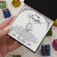 Heart-shaped silver necklace with sparkling crystals displayed in a gift box featuring a heartfelt message from a father to his daughter, surrounded by small wrapped presents.