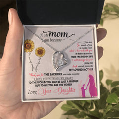 Silver heart pendant necklace with a sparkling central crystal, displayed in a gift box featuring a sentimental message from a daughter to her mother with sunflower and mother-child illustrations.