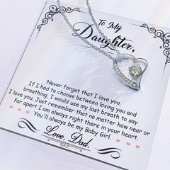 Silver heart-shaped necklace with a sparkling central crystal and smaller crystals along one side, displayed on a card with a heartfelt message to a daughter from her dad.