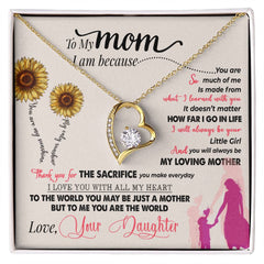 Heart-shaped gold necklace with a sparkling central crystal, displayed on a sentimental card featuring a loving message from a daughter to her mother, adorned with sunflowers and a silhouette of a mother and child.