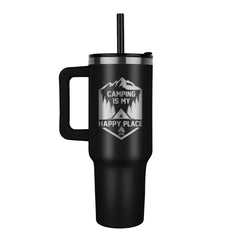 Black stainless steel tumbler with a handle and lid featuring laser-engraved text "Camping is my happy place" surrounded by mountain and tree graphics, ideal for outdoor enthusiasts.