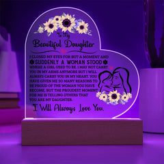 Heart-shaped acrylic plaque with a sentimental message to a daughter, featuring floral designs and an illustration of a mother and daughter, illuminated on a wooden base.