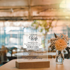 Clear acrylic plaque with a heartfelt romantic message to a wife, displayed on a wooden base, placed on a table beside a glass vase with dried flowers in a softly lit cozy room.