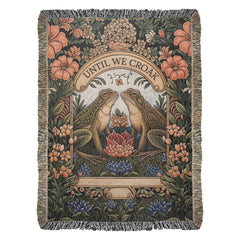 Woven cotton blanket featuring an intricate design with two frogs facing each other surrounded by colorful flowers and foliage, with the phrase "Until We Croak" at the top.
