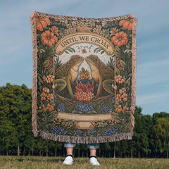 Woven cotton blanket featuring a detailed design of two frogs surrounded by flowers and foliage with the phrase "Until We Croak," ideal as a sentimental and cozy gift.