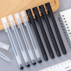 A set of black and translucent pens with caps arranged on a desk beside a spiral notebook and a ruler, showcasing a clean and organized workspace.