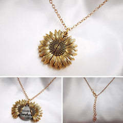 Gold-tone sunflower locket necklace with detailed petals, featuring a hidden engraved message inside and an adjustable chain clasp.