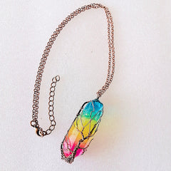 Delicate rainbow-colored quartz crystal pendant wrapped in silver wire forming a tree of life design, hanging from a fine silver chain necklace.