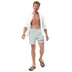 Man wearing blue animal patterned quick-dry swim trunks with a white open shirt and black flip-flops, smiling and walking confidently against a white background.