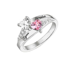 Silver personalized ring with two heart-shaped birthstones, one pink and one clear, engraved with the names Ryan and Scarlett, accented with small clear stones along the band.