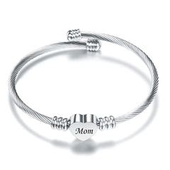 Silver twisted cable bracelet featuring a polished heart charm engraved with the word "Mom," designed as a sentimental gift for Mother's Day or special occasions.