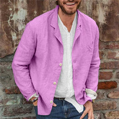 Man wearing a slim fit casual cotton linen blazer in purple over a white shirt and jeans, standing against a rustic brick and weathered wall background.