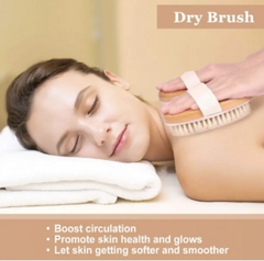 Woman lying on a towel while using a dry body brush with natural bristles to exfoliate and improve skin health and circulation.