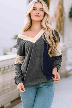 Woman wearing a multicolor polyester V neck sweater with color block design in charcoal, beige, and navy, paired with light blue jeans in an outdoor setting.