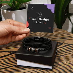 Hand holding a customizable card above a black braided leather bracelet with metal accents and an engraved clasp that says "love you forever," displayed on a black gift box on a wooden surface.